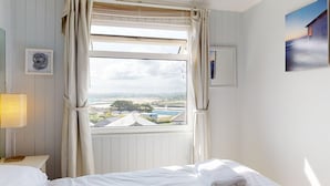 A bedroom with a large window, a bed, a bedside lamp, and a framed picture on the wall. - E28 HI-Up, Riviere Towans (Hayle)