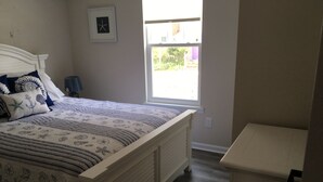 Une chambre à coucher avec un lit, une table de chevet, une fenêtre et un radiateur.
