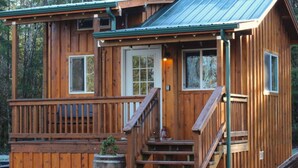 A wooden cabin with a porch, a front door, and a staircase leading to the entrance.