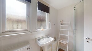 A bathroom with a window, a sink, a shelf, and a shower. - 15 Trevithick Court, Tolroy Manor (Hayle)