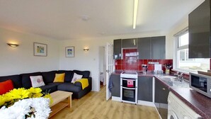 A compact living space with a sofa, coffee table, and a small kitchen area including a stove and sink.