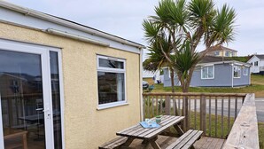 A wooden deck with a picnic table and chairs, a sliding glass door, and a small window.