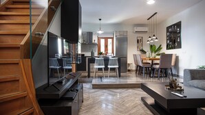 Een moderne keuken met een eethoek, een trap en een woonkamer met een bank en salontafel.