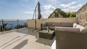 En tagterrasse med sofa, bord og parasol.