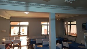 Habitación de hotel con comedor, ventanas amplias, ventiladores de techo y vistas al exterior.