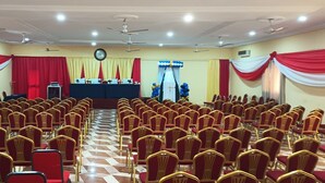 Un salón de conferencias con filas de sillas, un atril y un escenario.