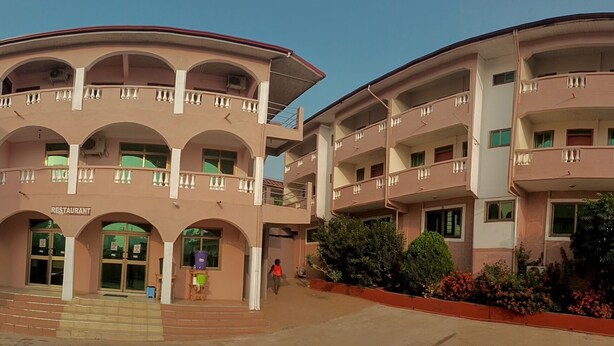 Un edificio de varios pisos con un patio central, que cuenta con balcones y la entrada a un restaurante.