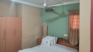 Un dormitorio con cama, armario, ventilador de techo y ventana con cortinas.