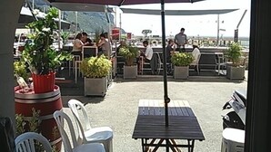 An outdoor seating area with tables and chairs, potted plants, and a large umbrella providing shade. - Unique panorama with the best view of Cassis (Cassis)