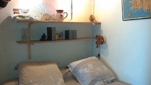 A bedroom with a bed, pillows, a shelf with decorative items, and a wall map. - Unique panorama with the best view of Cassis (Cassis)