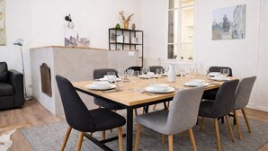 Un coin repas avec une table en bois dressée pour six personnes, entourée de chaises recouvertes d’un tissu gris.