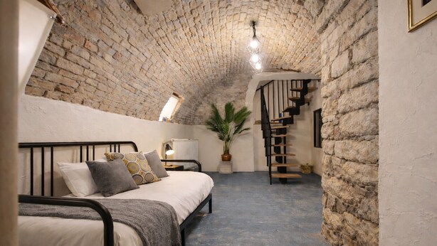 Une chambre à coucher avec un lit, une plante en pot, un radiateur et un escalier.
