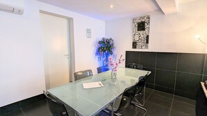 A modern dining area with a glass table, black chairs, a vase with pink flowers, a wall-mounted artwork, and a sign indicating quiet hours. - 3 Bedrooms Apartment in Amsterdam City Center (Amsterdam-Centrum)