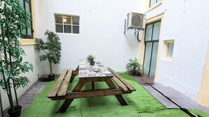 A courtyard with a wooden picnic table, potted plants, and a small window. - 3 Bedrooms Apartment in Amsterdam City Center (Amsterdam-Centrum)
