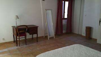 Une chambre à coucher avec un lit, un bureau, une chaise, un miroir et une porte.