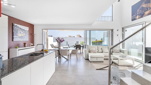 Un apartamento moderno con cocina, comedor y sala de estar. Cuenta con un ventanal grande, una escalera y vistas de la ciudad.