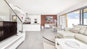 Una sala moderna con televisor de pantalla plana, un sofá y una zona de comedor con sillas.