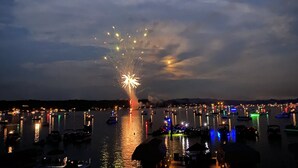 A nighttime view of a marina with boats and a fireworks display. - NEW Lake James, Indiana Waterfront Rental (Angola)