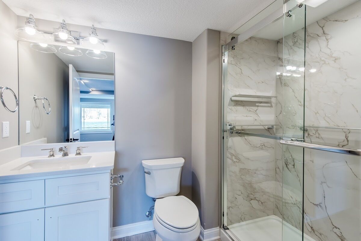 A bathroom with a white sink, a toilet, and a glass-enclosed shower.