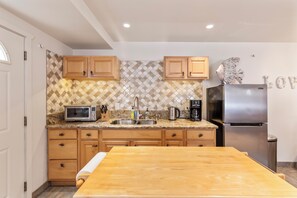 Enjoy cooking in this well-equipped kitchen with a stainless steel refrigerator, microwave, and sink.