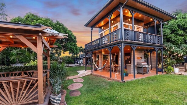 Una casa de dos pisos con balcón, mobiliario exterior y zona de barbacoa.
