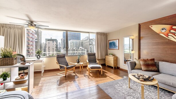 A modern living room with a city view, wooden flooring, and a ceiling fan. - Spacious renovated studio in downtown Waikiki (Honolulu)
