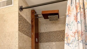 A shower area with beige tiles, a wooden shower door, and a tiled showerhead. - Spacious renovated studio in downtown Waikiki (Honolulu)