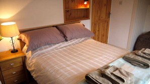 Ein Schlafzimmer mit Bett, Nachttisch, Lampe und einem Holzschrank.