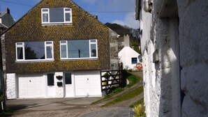 Ein zweistöckiges Haus mit Garage, heller Fassade und einem Steinziegeldach.