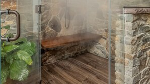 Eine gläserne Dusche mit Steinwänden und Holzboden.