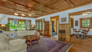 Ein großzügiges Wohnzimmer mit Holzbalkendecke, einem großen runden Tisch und einer Couch mit dekorativen Kissen.