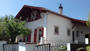 Ein zweistöckiges Gebäude mit rotem Dach, weißen Wänden und einem Balkon mit weißer Brüstung.