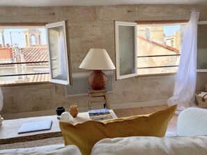 Une chambre d’hôtel avec un lit, une table sur laquelle se trouve un ordinateur portable, une lampe et une fenêtre donnant sur des immeubles.
