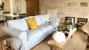 A cozy living room with a light-colored sofa, a wooden side table, and a rustic stone wall.
