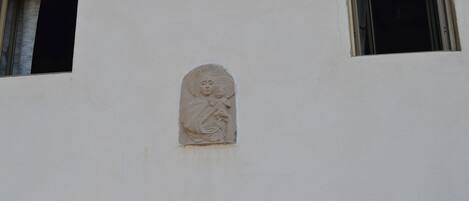 Fachada de edificio con un relieve de una figura, una ventana y una lámpara.