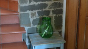 A staircase with terracotta steps leading to a stone wall, a small table with a green bottle, and a wooden door. - House -Mario- Single House CIN: IT046011C2K2ZAZUEE (Piano di Coreglia)
