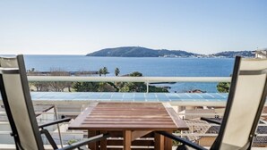 Un balcón con vista al mar, una mesa de madera y dos sillas.