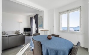Un soggiorno moderno con un divano grigio, una TV e un tavolo da pranzo con sedie in vimini.