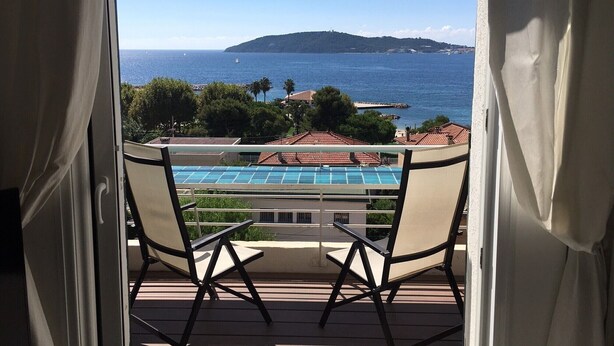 Un balcón con vista al mar, una silla y una piscina.