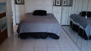 Quarto com cama, guarda-roupa e espelho.