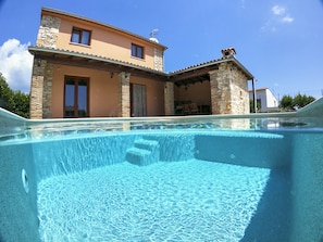 A two-story house with a swimming pool in the foreground.