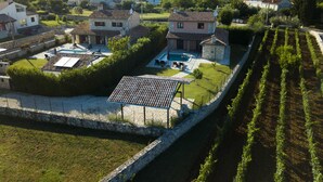 Ein Wohngebiet mit Swimmingpool, Steinmauern und einem Weinberg.