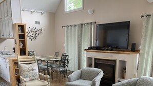 A spacious living room with a fireplace, a television, and a dining area with chairs and a table.