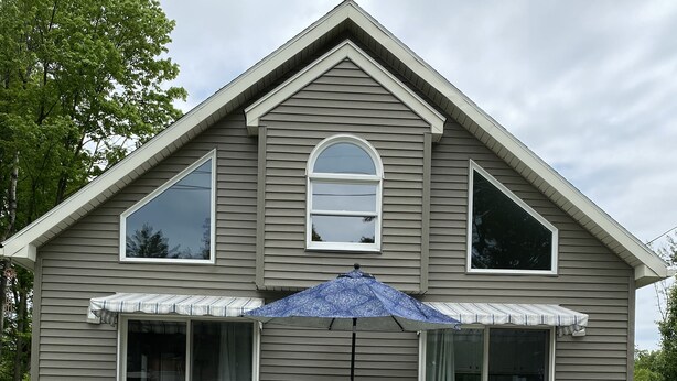 A house with a covered patio, a dining table, and two large flower pots.