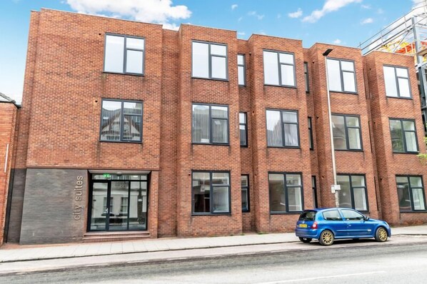 A multi-story brick building with a modern design, featuring large windows and a visible entrance. - City Suites by Guestz (Chester)