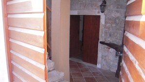 A narrow hallway with wooden paneling and stone walls, leading to a wooden door. - Mala Kapela is an authentic family home (Vrboska)