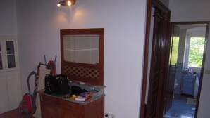 A room with a wooden dresser, a mirror, and a red vacuum cleaner. - Mala Kapela is an authentic family home (Vrboska)