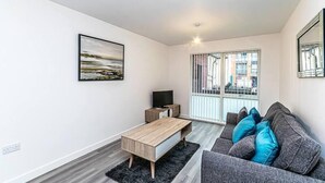 Una sala de estar moderna con un sofá gris, una mesa de centro de madera y un mueble para televisión.