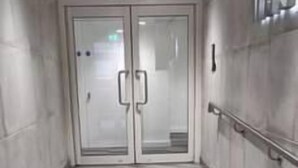 Un pasillo con piso de diseño espiga, puertas dobles y barandilla a la derecha.