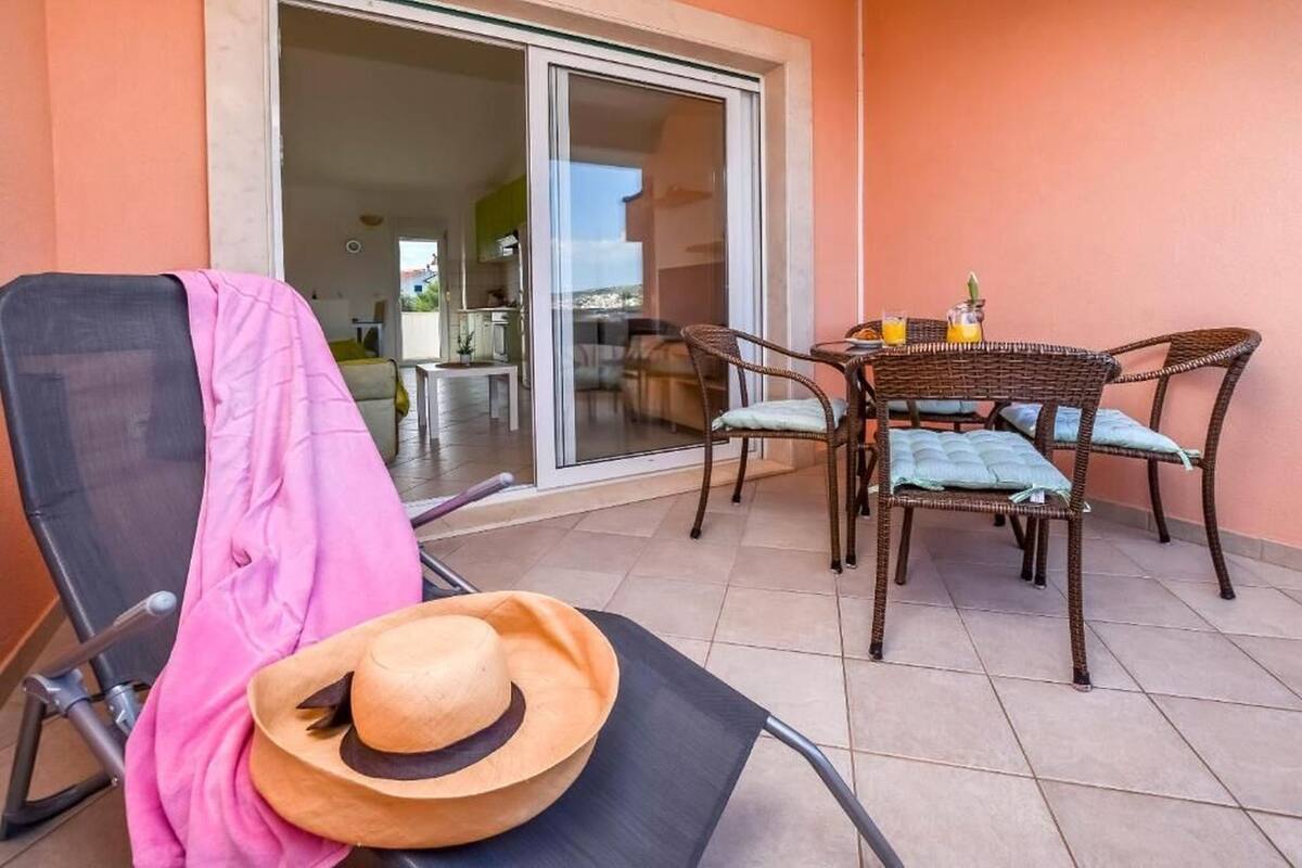 Un balcón con una silla, una mesa con sillas y una puerta corrediza de vidrio que da a un espacio interior.